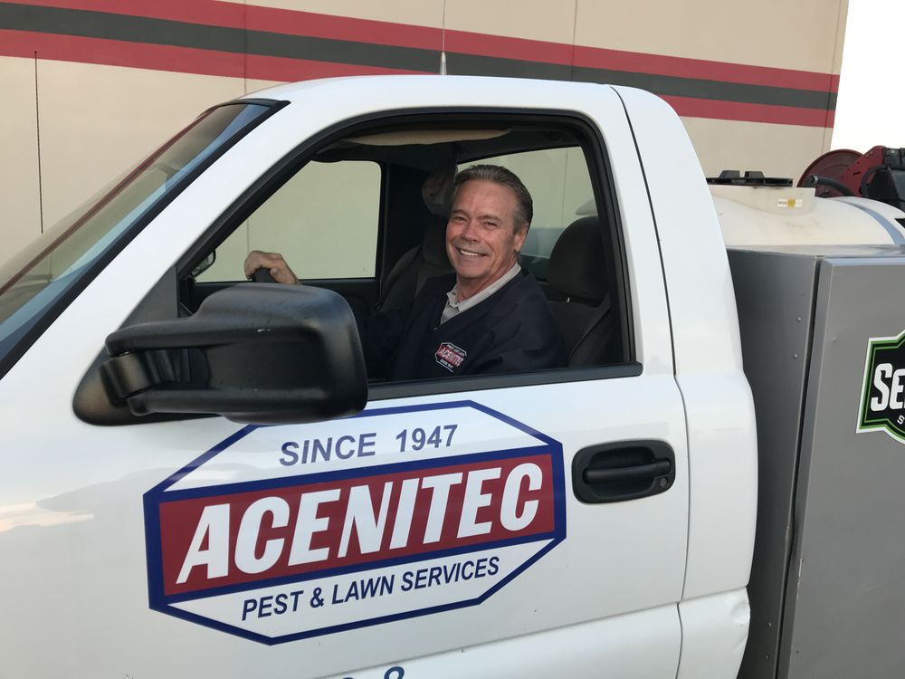 An Acenitec technician smiling from the window of a branded service truck
